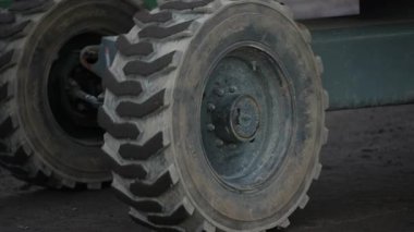 Ağır endüstriyel taşıt tekerlerinin, sert toprak yüzey üzerinde derin lastik izleri olan, inşaat nakliyesi ve makine işlemini ön plana çıkaran videoyu kapat