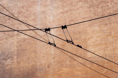 Kablo kıskaçları ve beton zemine dayanan süspansiyon donanımlarıyla elektrik tesisatı altyapı mühendisliğini temsil eden üstten güç iletim hatları