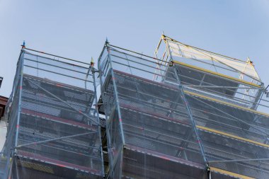 Kentsel yapı yenileme çalışmaları sırasında temiz gökyüzüne karşı yükselen güvenlik ağı ve metal platformları olan inşaat kuleleri