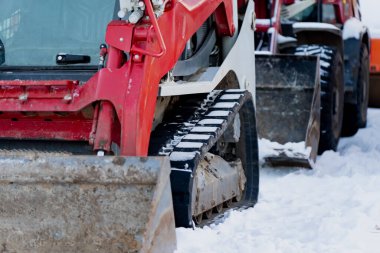 İzlenen kızak dümeni karda duran inşaat makineleri, kış mevsimi operasyonları sırasında kırmızı yük kovası ve şasiye yakın görüş