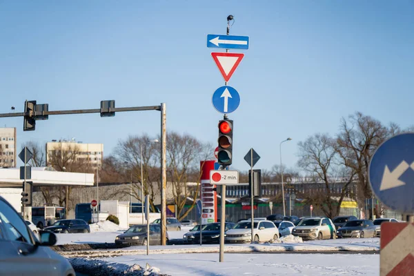 Trafik ışıkları, yön ve verim tabelaları, kuyruktaki arabalar ve karla kaplı kış manzarası