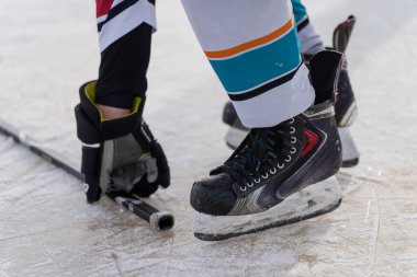 Patenli hokey oyuncusu çizik buz üzerinde sopaya uzanır, eldiveni kapatır, paten bıçağı ve üniformalı çoraplar, kış sporu eğitimi ve hazırlık konsepti.