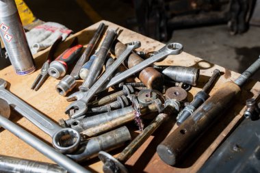 Yağlı metal aletler ve tırmalanmış bir bankta bağlayıcılar, ucu açık anahtarlar ve prizler ağır ekipman onarımı, bakım akışı ve engebeli iş ortamı öneriyor.