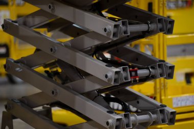 Endüstriyel makas kaldırma detayı çelik haç destekleri, çiviler ve hidrolik aktivatörleri, malzeme taşıma platformları için mühendislik tasarımını gösteriyor.