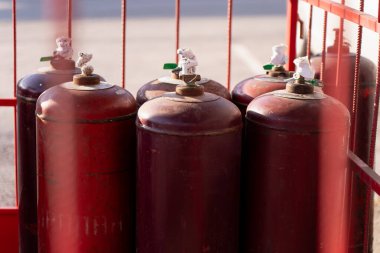 Sıkıştırılmış gaz şişeleri kırmızı bir depoda korunuyor. Endüstriyel taşıma standartları, tehlike kontrolü ve tesis tedarik sistemlerini temsil ediyor.