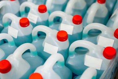 Mavi sıvıyla dolu plastik bidonlar ve kırmızı başlıklar, kimyasal depolama, ürün ambalajı ve depo envanterinin altını çizmek.