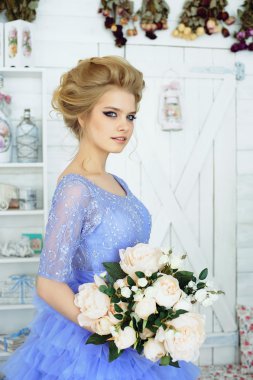 Çiçek buketi olan mavi elbiseli güzel bir kız.
