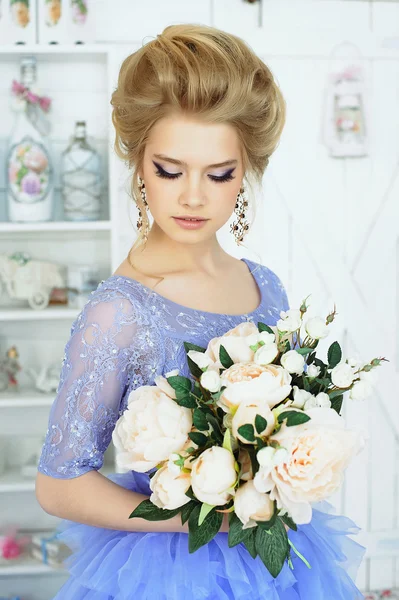 Mooi meisje in een blauwe jurk met een boeket bloemen — Stockfoto