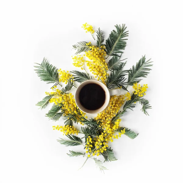 ブラック コーヒーのカップと白い背景に分離された黄色のミモザの花束のオーバー ヘッド ビュー — ストック写真