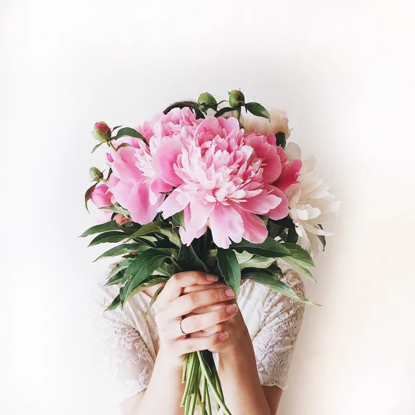 Mädchen mit rosa Pfingstrosen Strauß an weißer Wand — Stockfoto