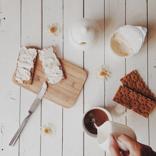 Manzanilla, taza de café con leche, azúcar y tostadas con pan y crema al fondo blanco — Foto de Stock