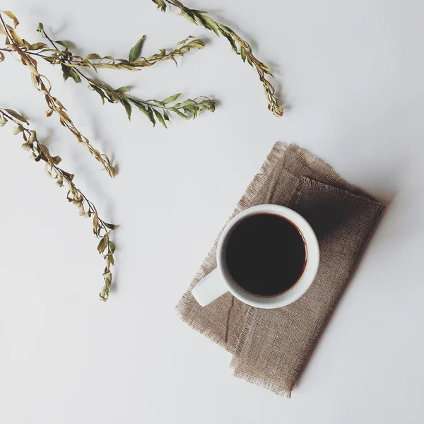 Taza de café, leche y flores secas en fondo blanco — Foto de Stock