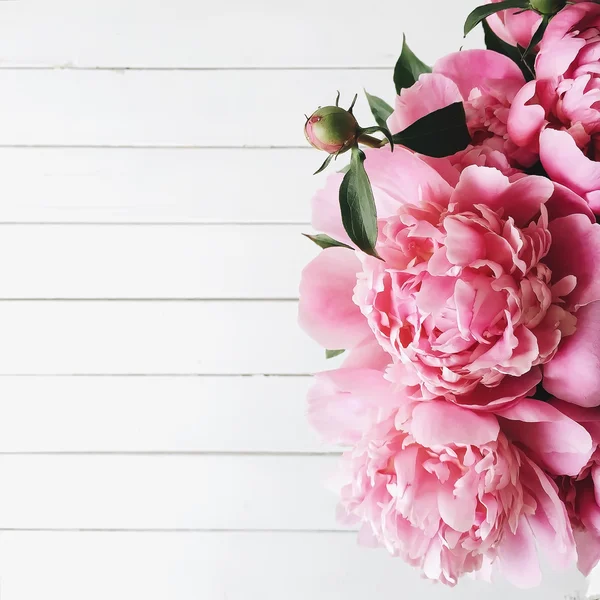 Vista aerea di bouquet di peonie rosa su sfondo di legno bianco — Foto Stock