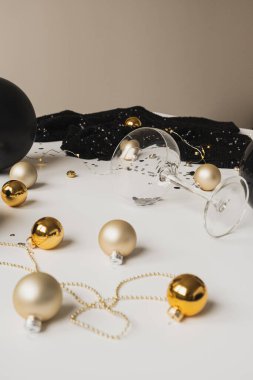 Noel / Yeni Yıl kutlaması konsepti. Şampanya bardağı, köpüklü konfeti, elbise, masada takılar. Minimalist tatil partisi kompozisyonu.