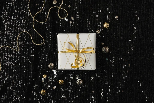 ティンセルのコンフェッティと黒輝く輝きの背景に蝶ネクタイと紙のギフトボックス クリスマスだ お正月はミニマルなコンセプトをお祝いします フラットレイ上からの眺め — ストック写真