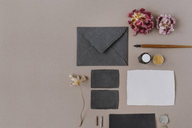 Düğün davetiyeleri. Kağıt levha, zarf, dolma kalem, bej arka planda mürekkep. Minimalist harfler, el yazısı şablonu. Düz yerde, üst tarafta. Boşluk modellemesini kopyala.