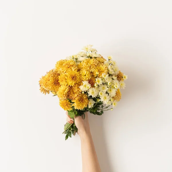 Flatlay of yellow and ginger fall wild flowers bouquet in women\'s hand isolated on white background. Flat lay, top view minimalistic floral composition. Valentine\'s Day, Mother\'s Day concept.