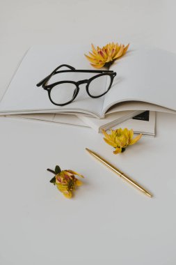 Minimalist ofis masası çalışma alanı. Boş kağıt sayfa defteri, bardaklar, sarı çiçek tomurcuğu, kırtasiye malzemesi. Blog, sosyal medya, web sitesi şablonu. Parlak iş, iş konsepti.