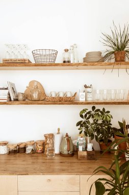 Şık bir ev mutfağı iç mimarisi. Ahşap raflar, tabaklar, kaplar, bardaklar, dekorasyonlar. Konforlu iç tasarım.