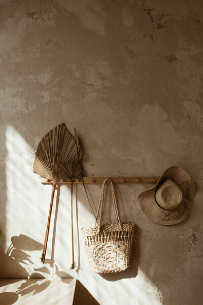 Boho style modern home interior design. Straw and rattan decorations against concrete wall. Warm sunlight shadows on the wall.