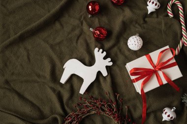 Papyonlu hediye kutusu ve Noel eşyaları: mücevherler, baston şekerler, buruşuk yeşil battaniyeli oyuncaklar. Tatil kutlaması geçmişi. Üst manzara, düz yatış. Noel / Yeni Yıl dekorasyonu.