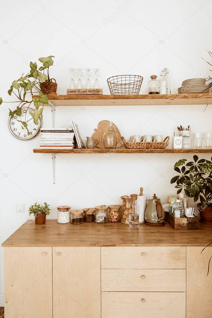 Modern boho style home kitchen interior concept. Wooden shelfs, dishes, utensils, decorations. Cozy comfortable bohemian interior design.