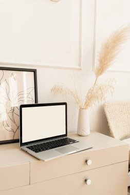 Boş ekran pastel bej kaplı dizüstü bilgisayar ve boho süslemeleri. Pampas çim buketi, fotoğraf çerçevesi. Model kopyalama alanı ile minimal boho tasarım şablonu.
