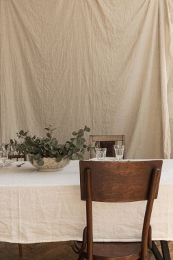 Bohem tarzı dekorasyonlu modern iç mekan tasarımı. Yemek masası, okaliptüs dalları, şarap bardakları, tabaklar, çatal bıçak takımı, masa örtüsü üzerinde sandalye. Boho tarzı konsept.