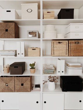 Modern ofis içi iç tasarım konsepti. Beyaz raflarda rattan kutular, kaktüsler, vazolar, süslemeler. Tarafsız bej ve beyaz konsept.