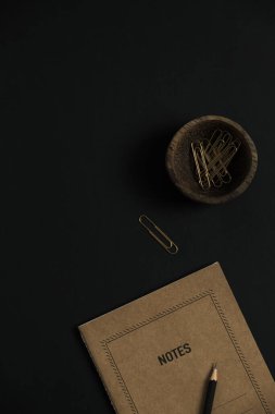 El işi defter kâğıdı, siyah arka planda kırtasiye malzemesi. Düz yatış, üst görünüm minimalist estetik yaşam tarzı kavramı.