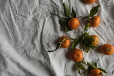 Çiğ portakallar, buruşuk kumaş üzerinde mandalinalar. Taze sağlıklı meyveler, yemek geçmişi. Flatlay, üst görünüm.