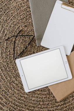 Boş fotokopi masası maket ekranı tableti, gözlük, pano, not defterleri yuvarlak hasır peçeteye. Üst görünüm minimal ofis çalışma alanı.