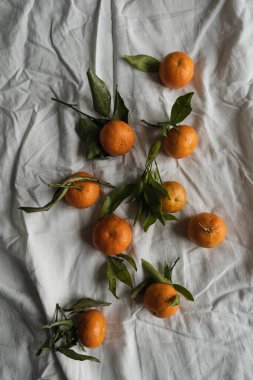 Çiğ portakallar, buruşuk kumaş üzerinde mandalinalar. Taze sağlıklı meyveler, yemek geçmişi. Flatlay, üst görünüm.