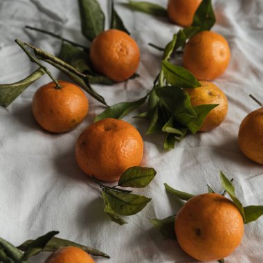 Çiğ portakallar, buruşuk kumaş üzerinde mandalinalar. Taze sağlıklı meyveler, yemek geçmişi.