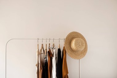 Estetik minimalist moda etkileyicisi blog konsepti. Yazlık kadın elbisesi, üstler, tişörtler, beyaz duvardaki saman şapka. Moda kadın kıyafetleri.