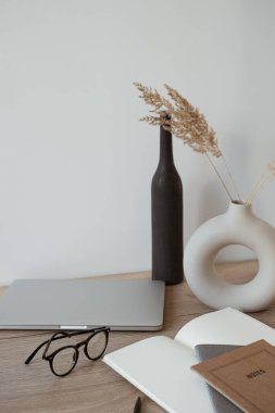 Dizüstü bilgisayar, defter, tahta arka planda gözlük. Merkez ofis çalışma alanı. Estetik blog, web, sosyal medya kompozisyonu.