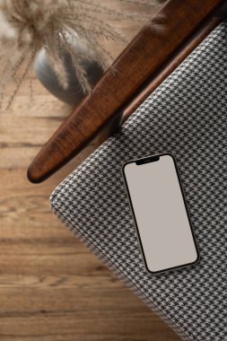 Vintage sandalyede boş ekran cep telefonu. Düz yatak, üst görünüm minimalist blog, web sitesi, uygulama şablonu. Uzayın akıllı telefon modelini kopyala.