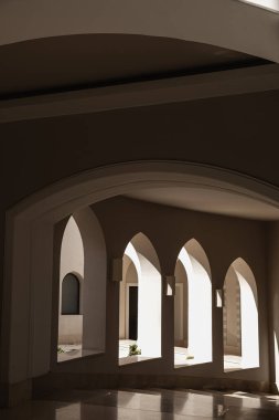 Pencereleri ve bej duvarlarında güneş ışığı gölgeleri olan modern doğu tarzı bir bina. Soyut minimal mimari tasarımı