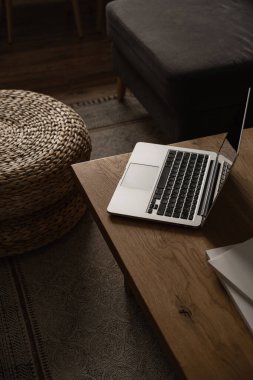 Estetik minimal ev, oturma odası iç tasarımı. Laptop bilgisayarlı tahta masa, rattan puf, tabure. Ofis masası çalışma alanı. Blog, web, sosyal medya konsepti. Evde çalış..