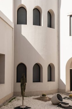 Pencereleri ve bej duvarlarında güneş ışığı gölgeleri olan modern doğu tarzı bir bina. Soyut minimal mimari tasarım kavramı