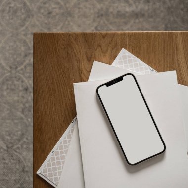 Boş ekranlı cep telefonu, ahşap masa ve halıda kağıt çarşaflar. Ofis masası çalışma alanı. Kadın, kadın patron estetik işi, kopya alanının şablonu. Düz yatış, üst görünüm