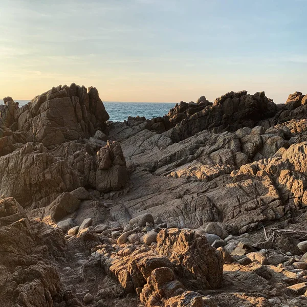 stock image Rough rock surface with sunlight shadows and view on sea and blue sky. Neutral landscape background