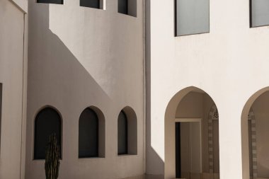 Pencereleri ve bej duvarlarında güneş ışığı gölgeleri olan modern doğu tarzı bir bina. Soyut minimal mimari tasarım kavramı