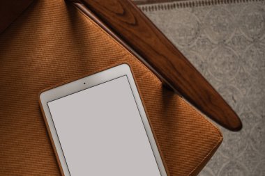 Vintage sandalyede boş ekran tableti. Düz yatak, üst görünüm minimalist blog, web sitesi, uygulama şablonu. Boşluk pedi modelini kopyala.
