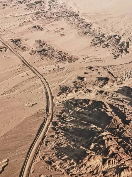 Aerial top view of desert with rock hills, mountains and lone road. Beautiful landscape background