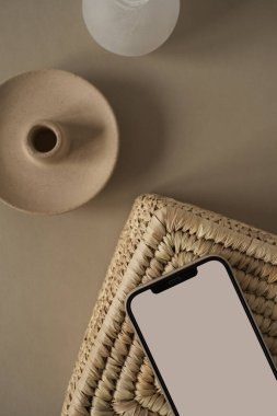Düz ekran cep telefonu, rattan tabut ve nötr bej arka plan. Merkez ofis çalışma alanı. Kadın, kız patron estetik işi, iş, uygulama şablonu taklit alanı. Düz yatış, üst görünüm