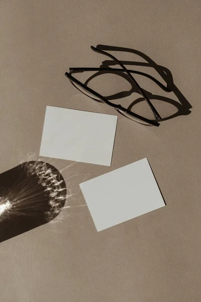 モックアップコピースペース付きのブランクペーパーシートカード ミニマルな高級ボヘミアン美的ビジネスブランドテンプレート 太陽の影を持つガラス 中性ベージュの背景のガラス フラットレイアウト トップビュー — ストック写真