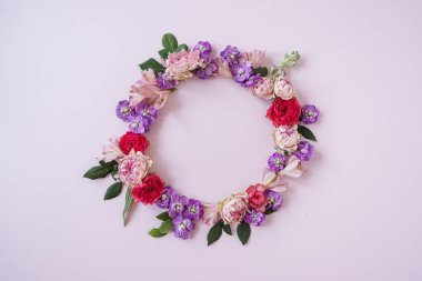 Soyut çiçekli estetik arka plan. Renkli gül çiçeklerinden oluşan yuvarlak çerçeveli çelenk. Pembe arka planda, boş fotokopi alanı modeli var. Güzel çiçekler ve taç yaprakları şablonu