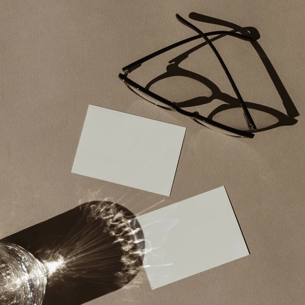 空白纸卡片 带有模拟复制空间 最小的豪华波希米亚美学商业品牌模板 有阳光阴影的水晶玻璃杯 中性米色背景的眼镜 平躺在地上 俯瞰四周 — 图库照片