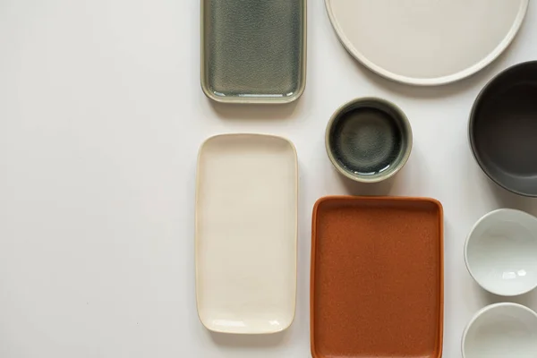 白色背景的空陶瓷圆碗和正方形盘子 平面放置 传统手工制作厨房用具概念的顶视图 — 图库照片